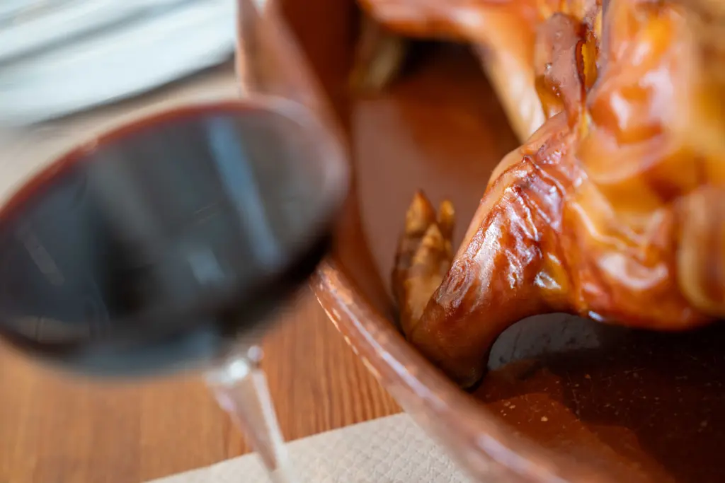 Cochinillo lechal asado, con una copa de vino tinto
